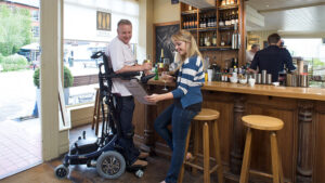 Một người đàn ông giao tiếp với mọi người khi đang ngồi trên xe lăn đứng.