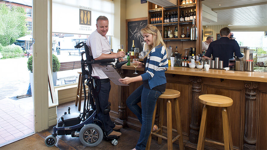 Một người đàn ông giao tiếp với mọi người khi đang ngồi trên xe lăn đứng.